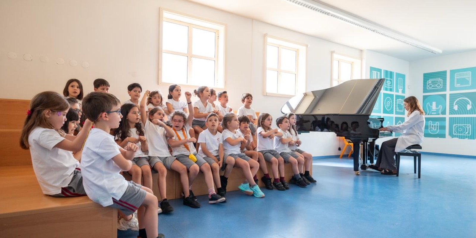 Turma sentada a ouvir piano na sala de música do Colégio João Paulo II