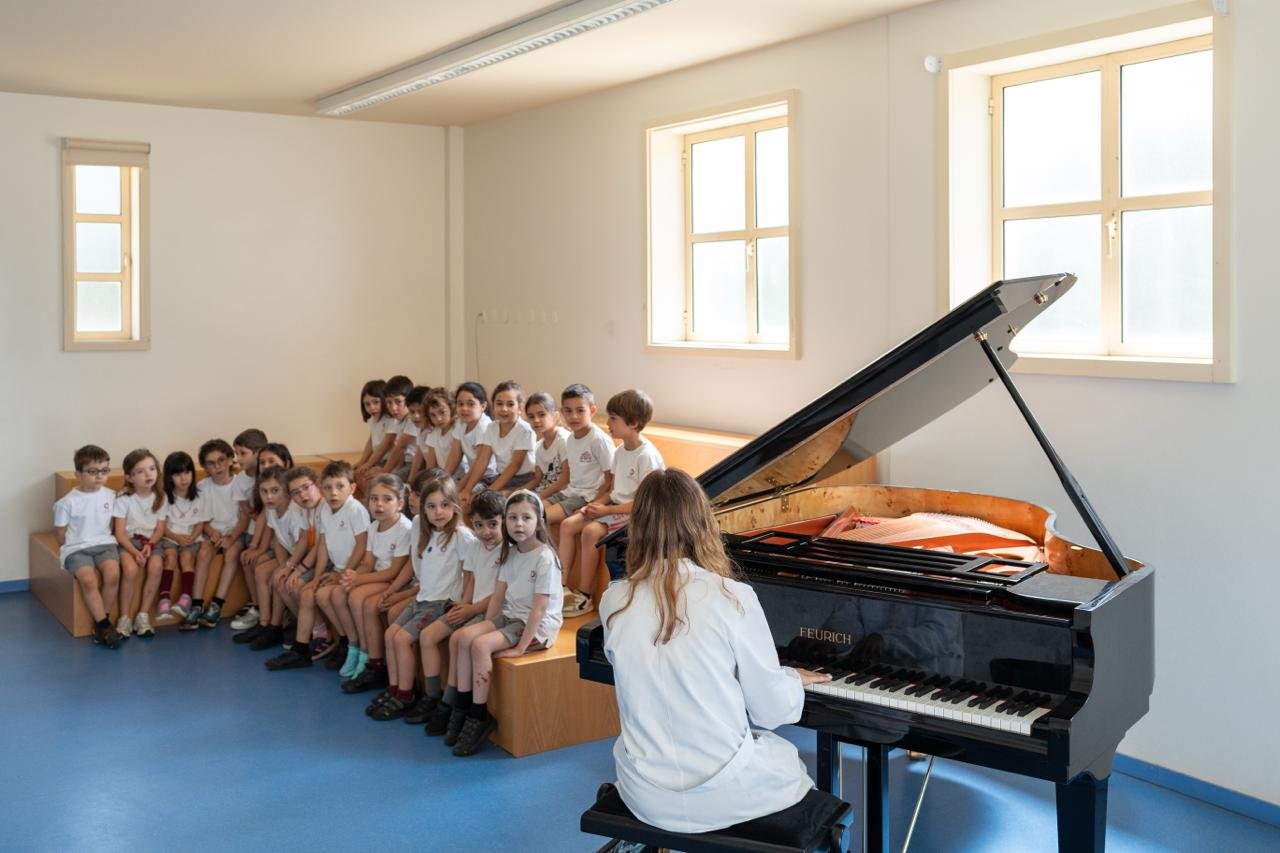 Alunos a acompanhar a música com as mãos, durante a aula